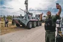  ?? BADERKHAN AHMAD/ASSOCIATED PRESS ?? A member of Asayish, the Kurdish internal security forces, takes a selfie Friday near a Russian military vehicle during a patrol near the Syrian and Turkish border.