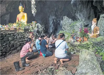  ?? YE AUNG THU/AFP/GETTY IMAGES ?? Relatives pray in Tham Luang cave area as rescue operations continue. Seeing the boys has boosted the mood of the family.