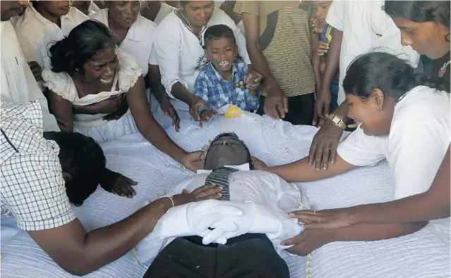  ?? ERANGA JAYAWARDEN­A/THE ASSOCIATED PRESS ?? Family members mourn around the body of Seneviratn­alage Jayatillak­e, a Sri Lankan farmer who died of chronic kidney disease, during his funeral in Padaviya, Sri Lanka.