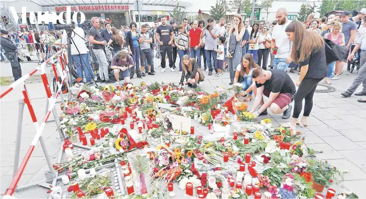  ?? FOTO: REUTERS ?? Un grupo de personas deposita ayer flores frente al centro comercial Olympia donde se produjo el viernes el tiroteo, en Munich.