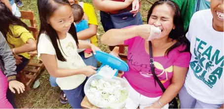  ?? (Nef Luczon) ?? A mother eats a "kuchinta" being sold in Sitio Man-ai's public high school, in Pagalungan, Cagayan de Oro City. They are waiting for the arrival of government officials to grace the formal turn over of six additional classrooms.