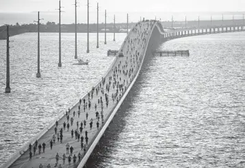  ?? ANDY NEWMAN/THE FLORIDA KEYS NEWS BUREAU ?? A 2nd run at Florida race: Some of the 1,000 registered competitor­s head to the highest point of the Seven Mile Bridge in the Florida Keys during the Seven Mile Bridge Run on Saturday, near Marathon. The contest was canceled in 2020 because of the pandemic, and this year’s field was runners who had registered last year.