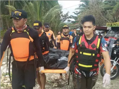  ??  ?? Rescuers carry a body, believed to be one of several fishermen who went missing at the height of Typhoon Phanfone that pummelled the central Philippine­s on Christmas Day, from the seashore in Borongan, Eastern Samar province, yesterday.