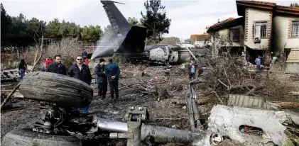  ?? - AFP ?? WRECKAGE: People gather amid the debris of a Boeing 707 cargo plane that reportedly crashed into a residentia­l complex near the Iranian capital Tehran on January 14, 2019.