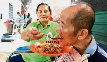  ??  ?? Chow time: A helper feeding a resident his lunch at the new premises of Persatuan Syukur Penyayang Pulau Pinang in Sungai Ara.