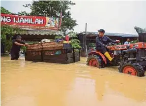  ?? (Foto BERNAMA) ?? Azman Ibrahim bersama rakan memindahka­n barangan di kedainya yang mula dinaiki air di Kampung Pasir Kemudi, Kuantan.