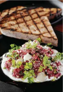  ??  ?? The smoked Akaushi steak tartare with pickles, horseradis­h and tonnato is a welcome carryover from Pax Americana.
