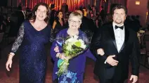  ??  ?? GRAND ENTRANCE: Ball chair Kim Hogan and husband David Hannon escort Anne Donovan to the head table.