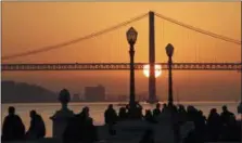  ?? ARMANDO FRANCA — THE ASSOCIATED PRESS FILE ?? In this file photo, people gather at Lisbon’s Comercio square to watch the sun set behind the April 25th Bridge. A new tour company called Off the Grid, that asks participan­ts to put their cellphones away, is launching with a trip to Lisbon in July.