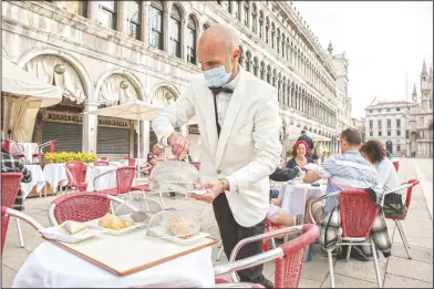  ?? (LaPresse/Filippo Ciappi) ?? A waiter works in St. Mark’s Square in Venice. Italy is gradually opening after six months of rotating virus closings allowing outdoor dining.