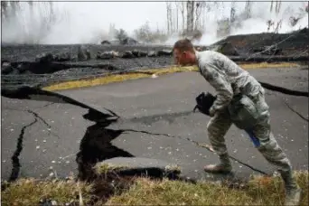  ?? JAE C. HONG - THE ASSOCIATED PRESS ?? U.S. Air National Guardsman John Linzmeier looks at cracks as toxic gases rise near by in the Leilani Estates subdivisio­n near Pahoa, Hawaii Friday. Hawaii residents covered their faces with masks after a volcano menacing the Big Island for weeks...