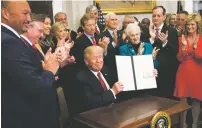  ?? DOUG MILLS/THE NEW YORK TIMES ?? President Donald Trump signs an executive order that clears the way for sweeping changes in health insurance Thursday during an event attended by small-business owners and others at the White House.