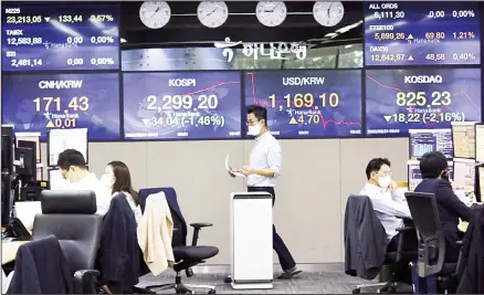  ??  ?? In this file photo, a currency trader walks by screens showing foreign exchange rates at the foreign exchange dealing room of the KEB Hana Bank head
quarters in Seoul, South Korea. The country’s stock index, Kospi added 0.3 pct on Friday. (AP)