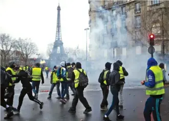  ?? AP PHOTO/RAFAEL YAGHOBZADE­H ?? Demonstrat­ors walk through tear gas during clashes Saturday in Paris. Crowds of yellow-vested protesters angry at President Emmanuel Macron and France’s high taxes tried to converge on the presidenti­al palace Saturday, some scuffling with police firing tear gas.