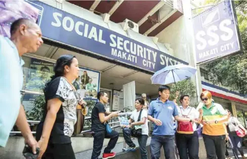  ?? ABS-CBN ?? Civilians walk past a Social Security System branch in Makati City.