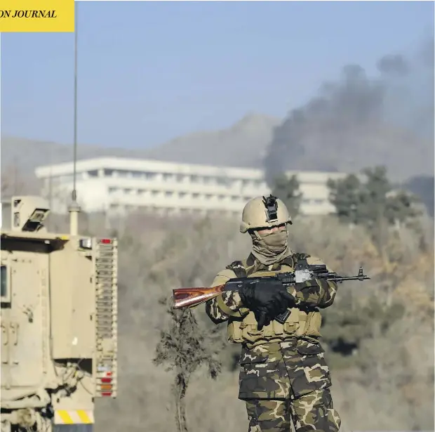  ?? WAKIL KOHSAR / AFP / GETTY IMAGES ?? An Afghan security officer stands guard as black smoke rises from the Interconti­nental Hotel following a weekend attack in Kabul.