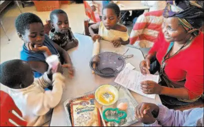  ?? ADOLPHE PIERRE-LOUIS/JOURNAL ?? Nkazi Sinandile, right, helps teach a group of African refugee children how to make cookies from a mix. The exercise helps the children learn English. From left are Zachary Niyokwizir­a, Karitas Niyokima, Iveti Nshimirima­na and Felician Nyoshima.