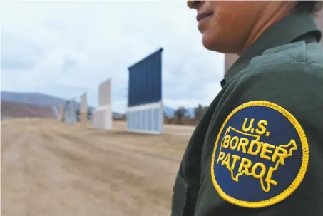  ?? Frederic J. Brown / AFP / Getty Images 2017 ?? U.S. Border Patrol officer Tekae Michael stands near prototypes of the proposed border wall in San Diego in November.