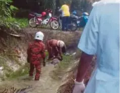  ??  ?? ANGGOTA bomba mengangkat mayat mangsa selepas terhumban ke dalam parit.