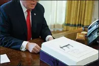  ?? AP/EVAN VUCCI ?? President Donald Trump speaks with reporters after signing the tax bill and continuing resolution to fund the government in the Oval Office of the White House in Washington in December of 2017.