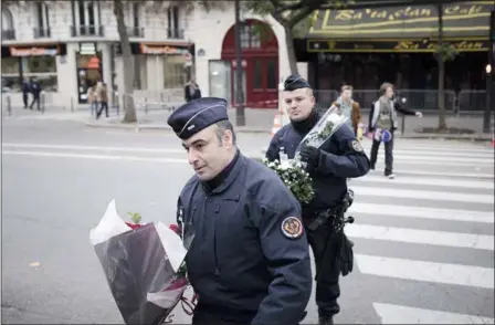  ?? KAMIL ZIHNIOGLU — THE ASSOCIATED PRESS ?? Police officers hold flowers given by people near the Bataclan concert hall Saturday in Paris. A concert by British pop legend Sting is marking the reopening of the Paris’ Bataclan concert hall one year after the terror attack.