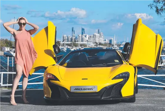  ?? Picture: STEVE HOLLAND ?? Brittany Capps checks out a yellow convertibl­e McLaren Spider 650s at the Spit which retails at almost $500,000.