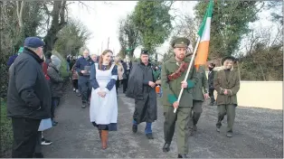  ?? (Photo: Katie Glavin) ?? Shane Tobin, dressed in a Volunteers uniform leading the procession to the monuments in Glenbrohan­e on Sunday in the presence of Jean O’Connell (dressed in 1920’s nurse uniform); piper, David Tobin’s great grandnephe­w (hidden) and Aishling O’Connell (Cumann na mBan uniform).