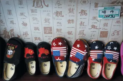  ?? ANDY WONG — THE ASSOCIATED PRESS ?? Chinese-made children shoes carrying a Chinese map and U.S. flags are on display for a sale at a shop in Beijing. China announced it filled a World Trade Organizati­on challenge Monday to U.S. President Donald Trump’s proposal for a tariff hike on $200 billion of Chinese goods, reacting swiftly amid deepening concern about the economic impact of their spiraling technology dispute.