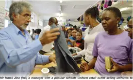  ??  ?? Mr Ismail Jina (left) a manager with a popular schools uniform retail outlet selling uniforms to clients at their shop at the corner of Herbert Chitepo Street and 8th Avenue yesterday