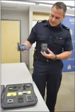  ??  ?? Staff Sgt. Chad Holt shows how the body-worn cameras worn by Medicine Hat Police Service officers works. The six-month pilot project has been extended to a full year.