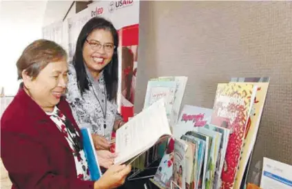  ?? / CONTRIBUTE­D FOTO ?? LEARNING MATERIALS. Dr. Elisea dela Torre and Dr. Casiana Caberte both of DepeEd Bohol review USAID-donated learning materials at the completion ceremony for USAID’s P1.9 billion Basa Pilipinas project.