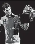  ?? DITA ALANGKARA/AP ?? Novak Djokovic admires his trophy after rallying for a victory in Sunday’s final.