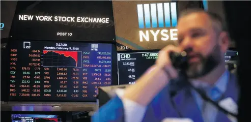  ?? MICHAEL NAGLE / BLOOMBERG ?? A monitor displays stock informatio­n as a trader works on the floor of the New York Stock Exchange on Monday. U. S. stocks plunged, sending the Dow Jones Industrial Average down almost 1,600 points.