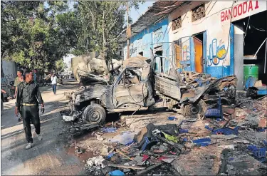  ?? Picture: AFP ?? CRUMPLED WRECK: Residents check out the scene of a blast, a day after two car bombs exploded in Mogadishu