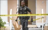  ?? ANDRES LEIVA / THE PALM BEACH POST ?? A Jupiter police officer carries a bag away from the townhouse in Jupiter’s Abacoa neighborho­od where a fight broke out early Tuesday, leading to two stabbings and two arrests.