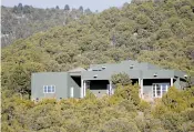  ?? LUIS SÁNCHEZ SATURNO/NEW MEXICAN FILE PHOTO ?? A home on Camino De Cruz Blanca visible from St. John’s College was restuccoed a deep forest-green. Under city code, houses in historic districts must be finished in ‘brown, tan or local earth tones.’ The homeowners Jimmy and Jennifer Day have appealed...