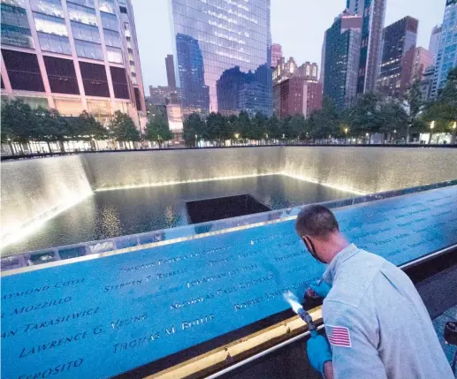  ?? MARK LENNIHAN/AP PHOTOS ?? Kevin Hansen, an engineer at the 9/11 Memorial & Museum, uses a torch to clean and burnish the names cut into the metal plates that border the south pool.
