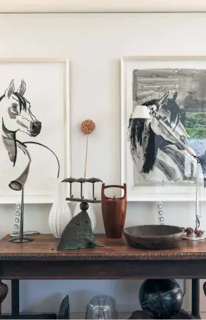  ??  ?? THIS PAGE (from left) Diana’s studies of horses look down on a teak ice bucket imported by her father and a fish sculpture by Paul Dibble on an old refectory table. A seal skull sits inside an antique Chinese footbath on a coffee table from ECC; the painting is by Simon McIntyre and the ply drum is a handy place to stash togs and towels.