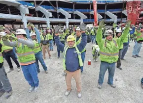  ?? MIKE DE SISTI / MILWAUKEE JOURNAL SENTINEL ?? Steve Finn (center), a plumber with the Hooper Corp., and Troy Kuebler (right), a Grunau Co. sheet metal journeyman, are joined by hundreds of others for morning stretches.