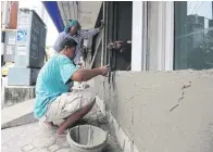  ??  ?? Workers build a concrete barrier at an entrance to a home in central Phetchabur­i.