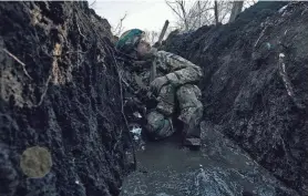  ?? LIBKOS/AP ?? A Ukrainian soldier takes cover in a trench under Russian shelling on the front line close to Bakhmut, Ukraine, Sunday. Russian forces that invaded Ukraine just over a year ago have been bearing down on Bakhmut for months.