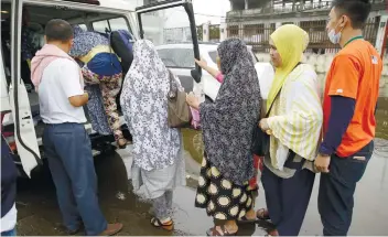  ?? AP FOTO ?? ESCAPE. Rohaina Salic, second from right, waits to board their vehicle with family and relatives at the provincial government headquarte­rs in Marawi City on June 8, after they were given safe passage during a brief ceasefire.