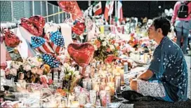  ?? PAUL RATJE/GETTY-AFP ?? In August, a mourner sits at a memorial for the shooting victims at a Walmart in El Paso.