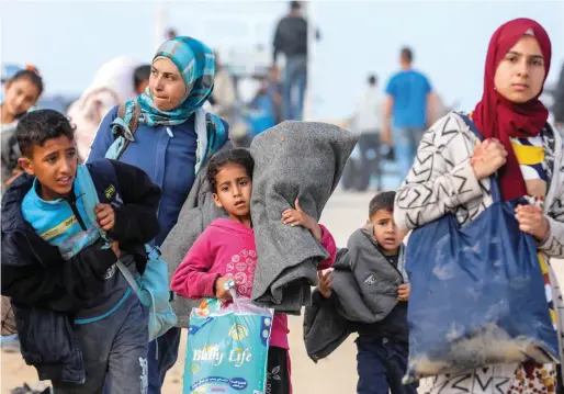  ?? — REUTERS ?? Palestinia­ns make their way as they attempt to return to their homes in north Gaza through an Israeli checkpoint on Monday.