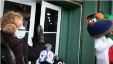  ?? NAncy LAnE / hErALd stAFF ?? IT’S NO GAME: Susan Johansen, who just received a vaccinatio­n Monday at Fenway Park, is met outside the ballpark by mascot ‘Wally the Green Monster’ and members of the media.