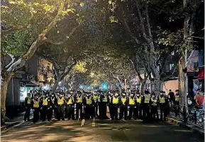  ?? AP ?? Chinese police officers block off access to a site where protesters had gathered in Shanghai.