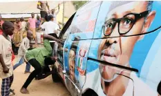  ?? | Reuters ?? SUPPORTERS of Nigeria’s President Muhammadu Buhari celebrate near a vehicle decorated with pictures of him in Yola, Adamawa State, Nigeria.