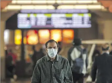  ?? Irfan Khan Los Angeles Times ?? A COMMUTER wears a mask while walking inside Union Station last month in downtown Los Angeles.