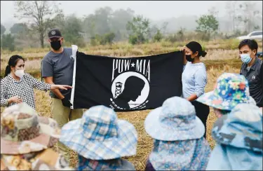  ?? (AP/Defense POW/MIA Accounting Agency/U.S. Army Sgt. 1st Class Michael O’Neal) ?? Personnel assigned to the Defense POW/MIA Accounting Agency talk Feb. 16 about The National League of Families POW/MIA flag to local Thai workers during excavation operations in Lampang Province, Thailand.