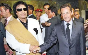  ?? PATRICK KOVARIK/AFP ?? Then-French President Nicolas Sarkozy shakes hands with then-Libyan leader Muammar Gaddafi (left) upon his arrival for an official visit to Tripoli, Libya, on July 25, 2007.